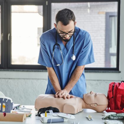 Young,Paramedic,In,Blue,Uniform,And,Eyeglasses,Practicing,Chest,Compressions